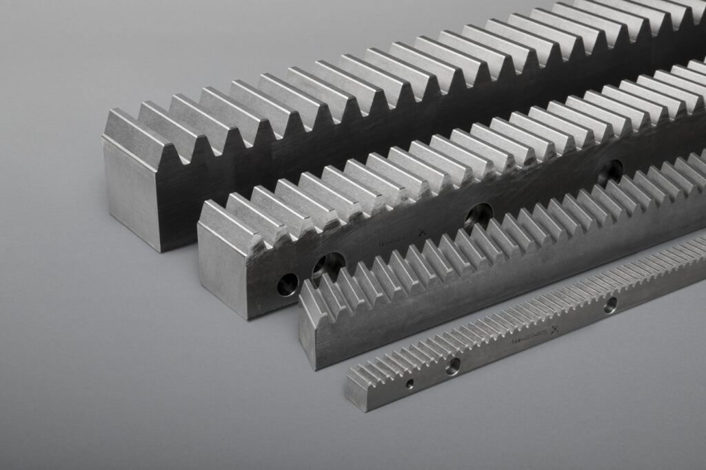 Unser Sortiment umfasst gerad- und schrägverzahnte Zahnstangen in geschliffener sowie gefräster Ausführung. Wir fertigen sowohl Standards als auch Sonderlösungen in diversen Modulen, Abmessungen und Werkstoffen, auch gehärtet und beschichtet.